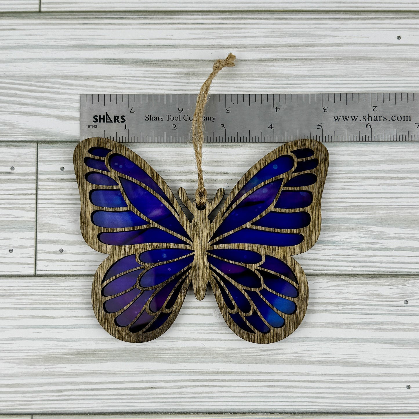 Butterfly suncatcher made from wood and acrylic lying flat with a ruler showing the approximate width.