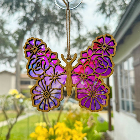 Floral butterfly suncatcher made from wood and acrylic hanging in window shown in the light stain option.