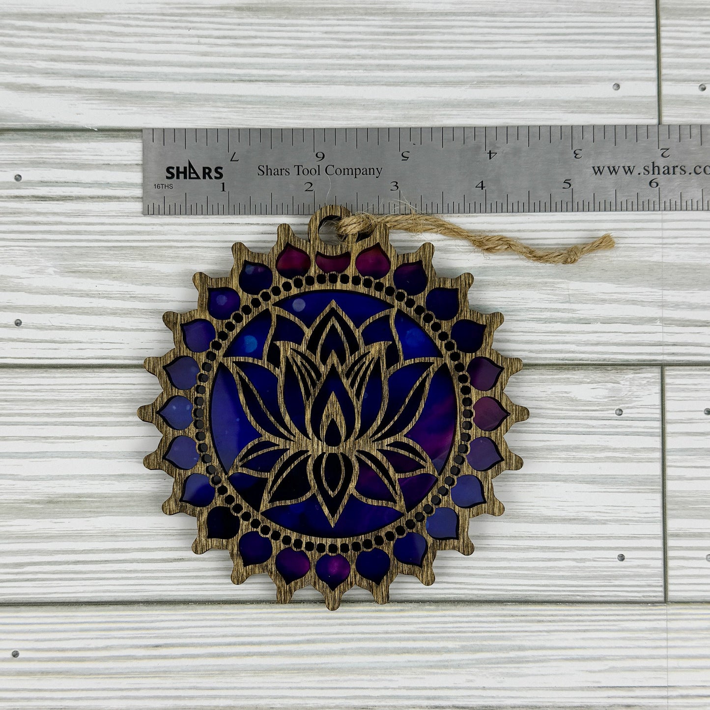 Lotus flower suncatcher made from wood and acrylic lying flat with a ruler showing the approximate width.