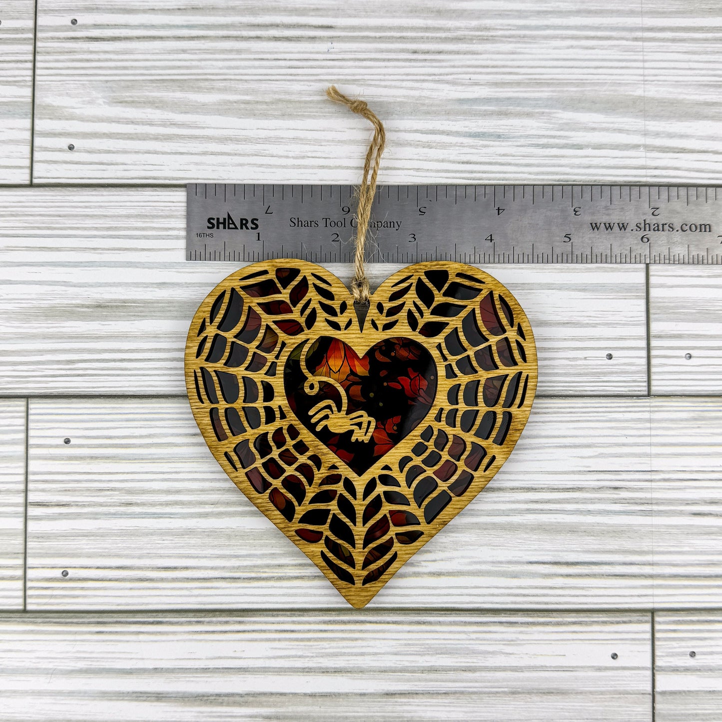 Spiderweb heart shaped suncatcher made from wood and acrylic lying flat with a ruler showing the approximate width.