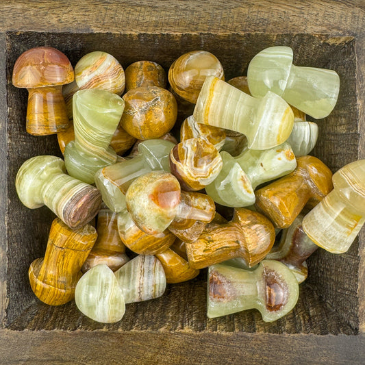 Collection of polished green and brown banded calcite stone mushrooms on a wooden surface