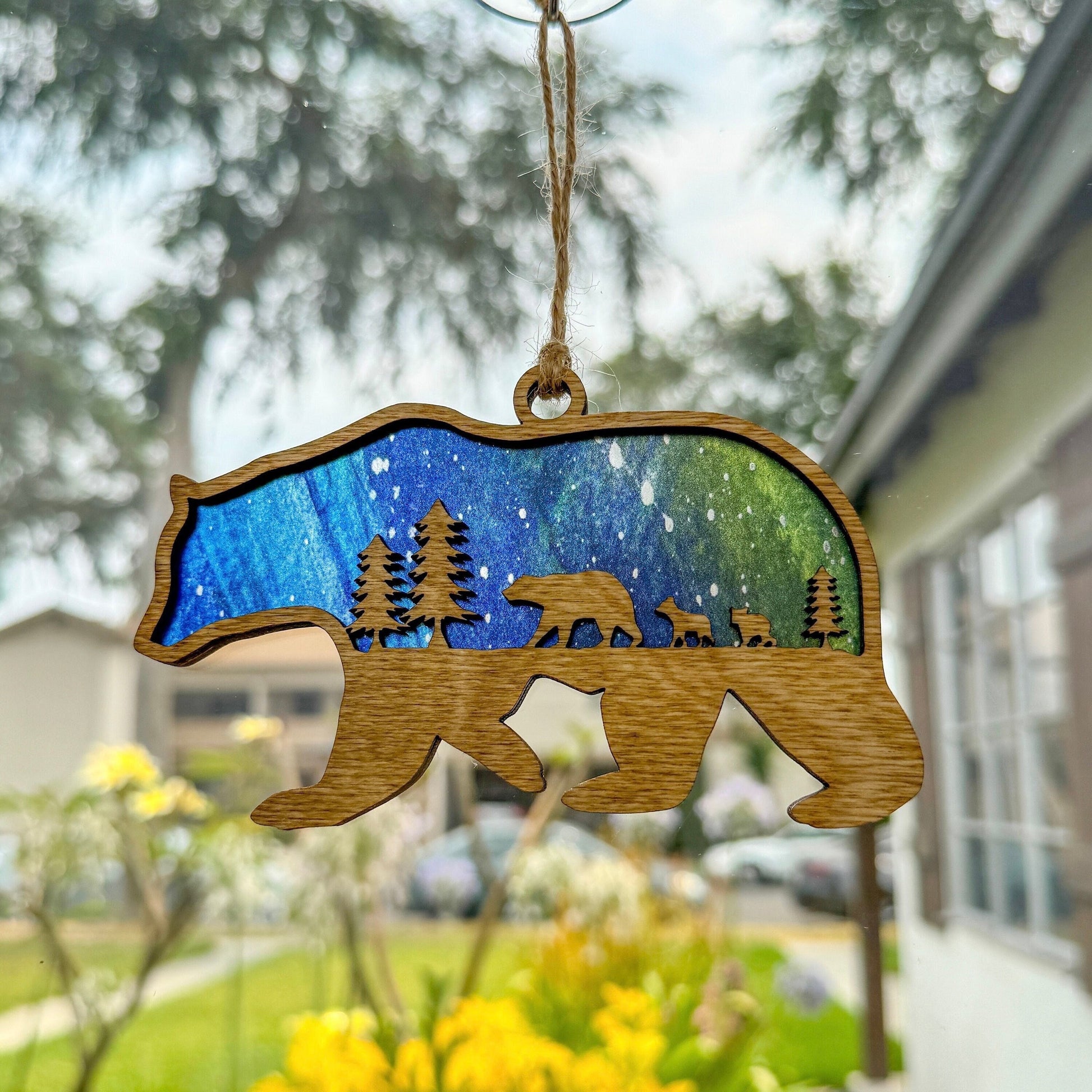 Bear suncatcher made from wood and acrylic hanging in window shown in the light stain option.