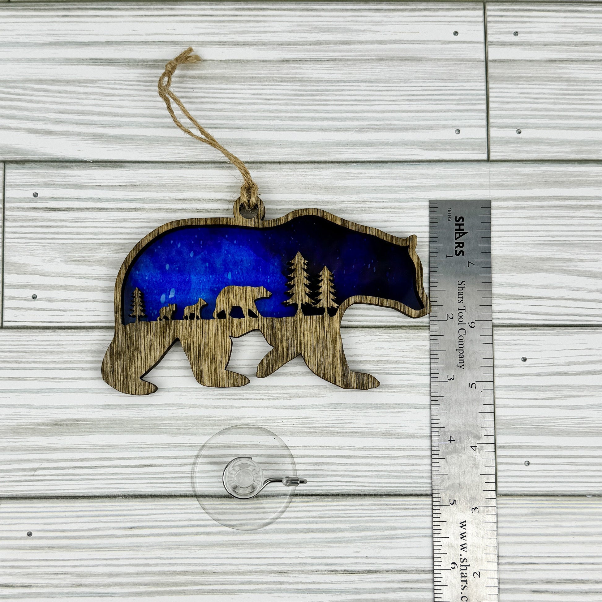 Bear suncatcher made from wood and acrylic lying flat with a ruler showing the approximate height.