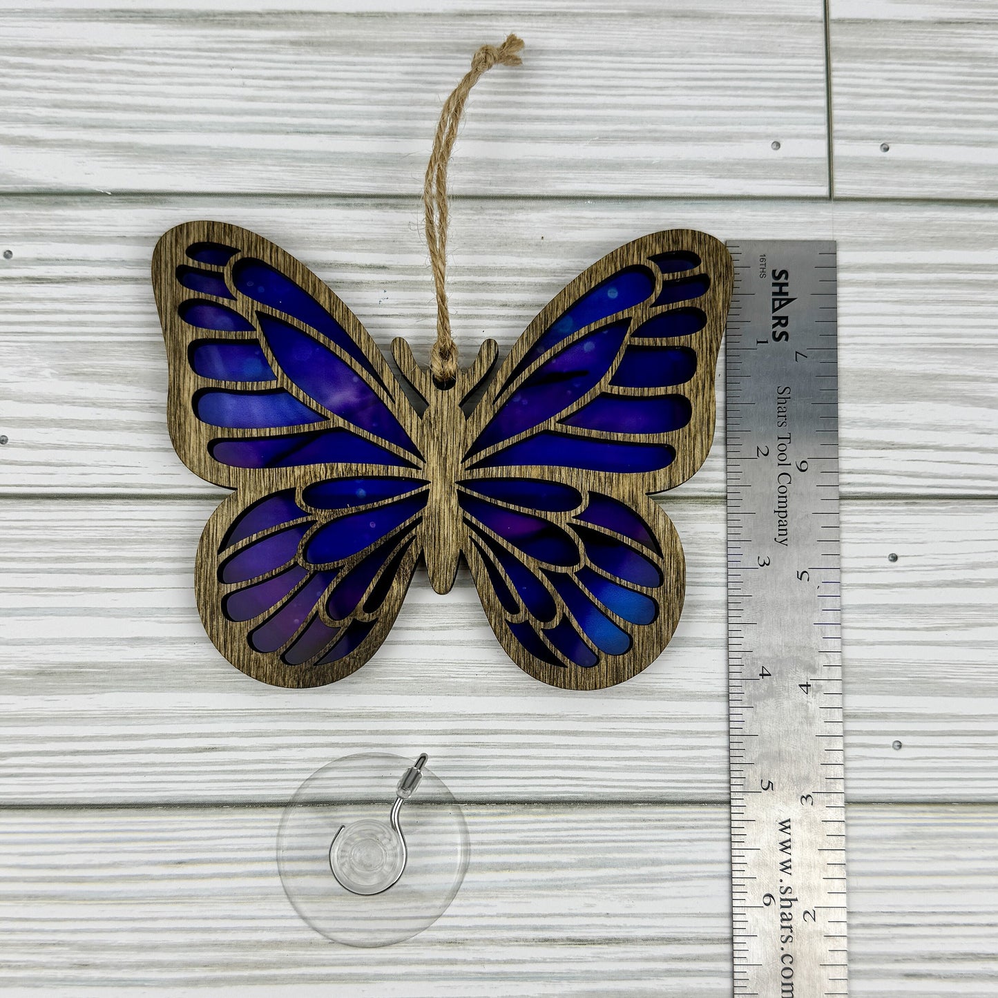 Butterfly suncatcher made from wood and acrylic lying flat with a ruler showing the approximate height.