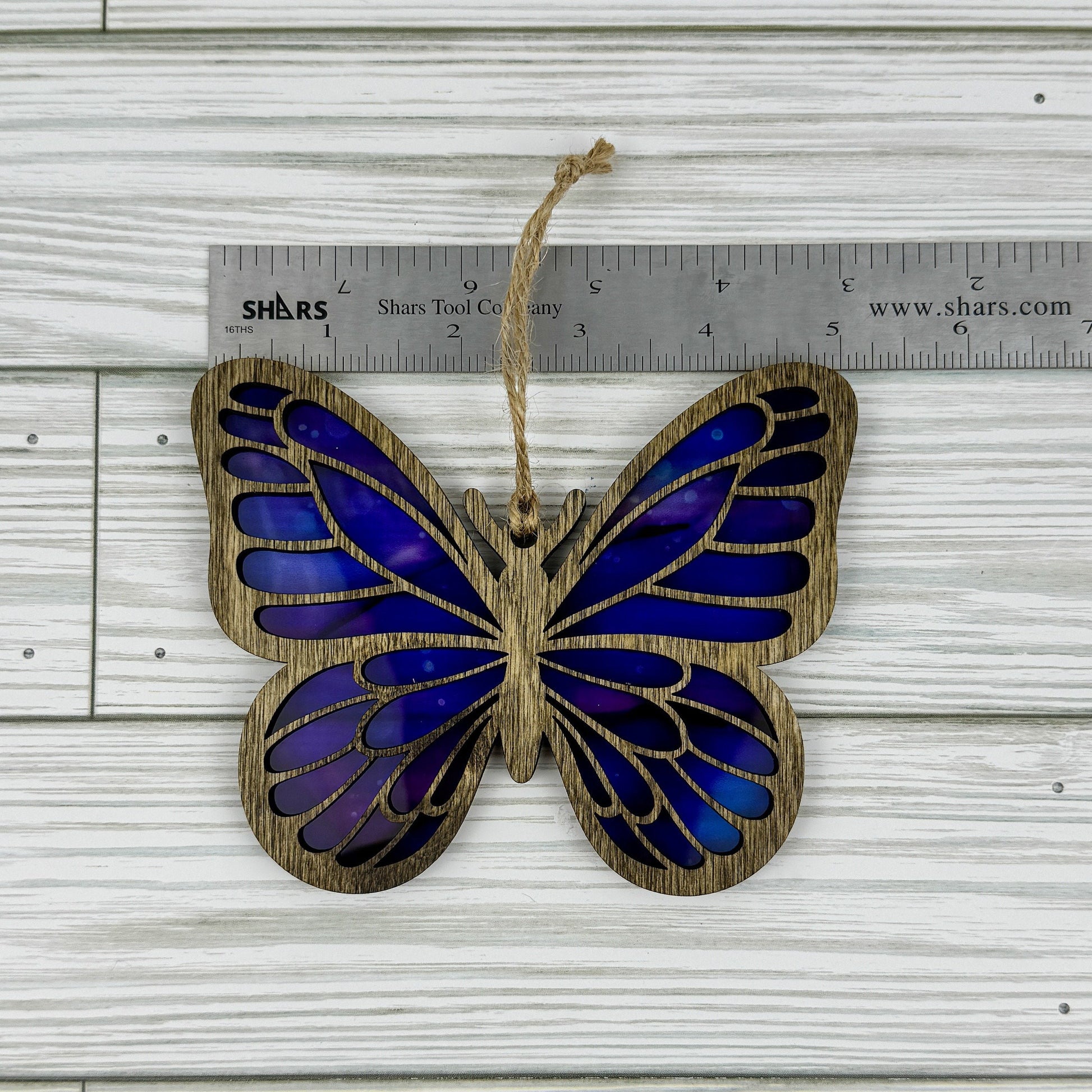 Butterfly suncatcher made from wood and acrylic lying flat with a ruler showing the approximate width.