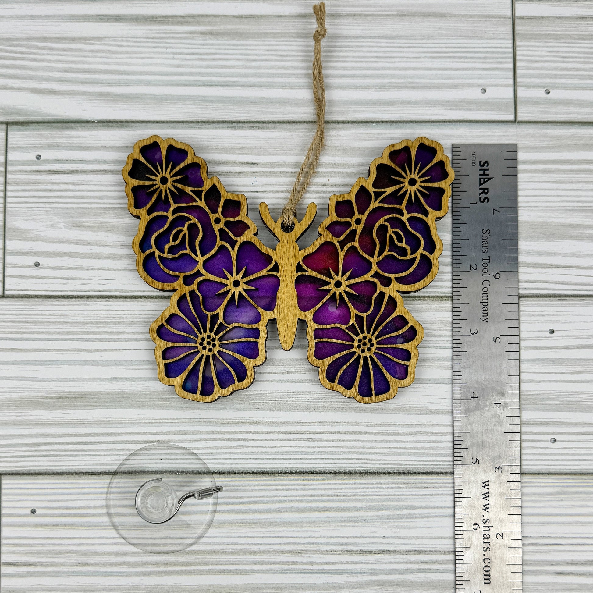 Floral butterfly suncatcher made from wood and acrylic lying flat with a ruler showing the approximate height.