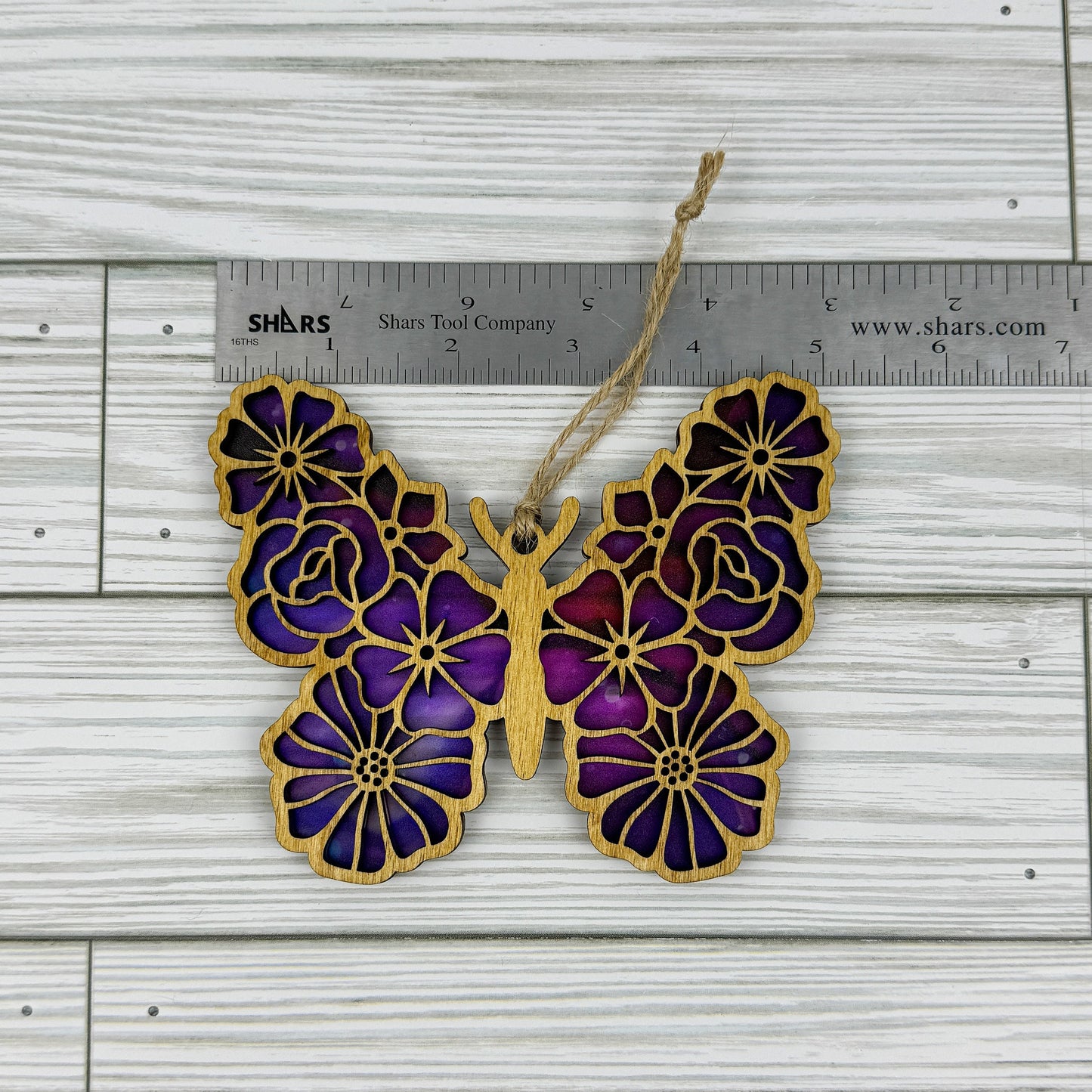 Floral butterfly suncatcher made from wood and acrylic lying flat with a ruler showing the approximate width