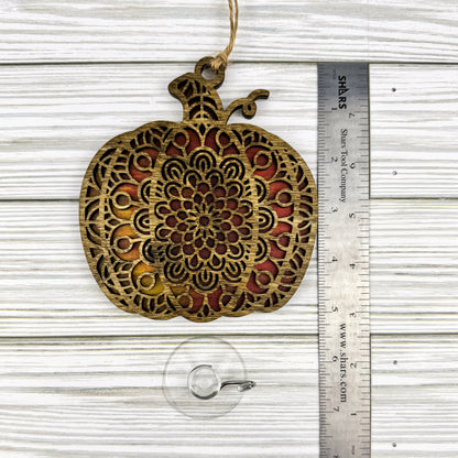 Geometric pumpkin suncatcher made from wood and acrylic lying flat with a ruler showing the approximate height.