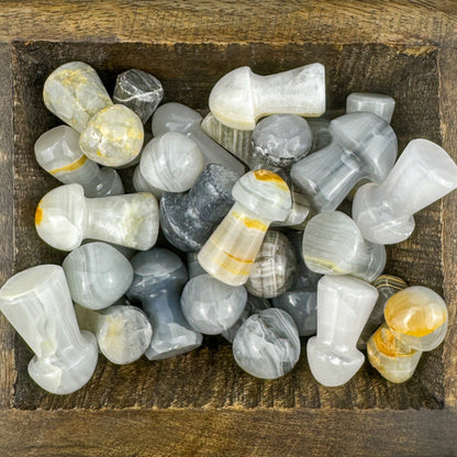 Collection of gray and white carved banded calcite stones in a wooden box
