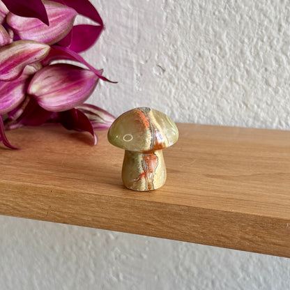 Decorative calcite stone mushroom on a wooden surface with pink flowers in the background