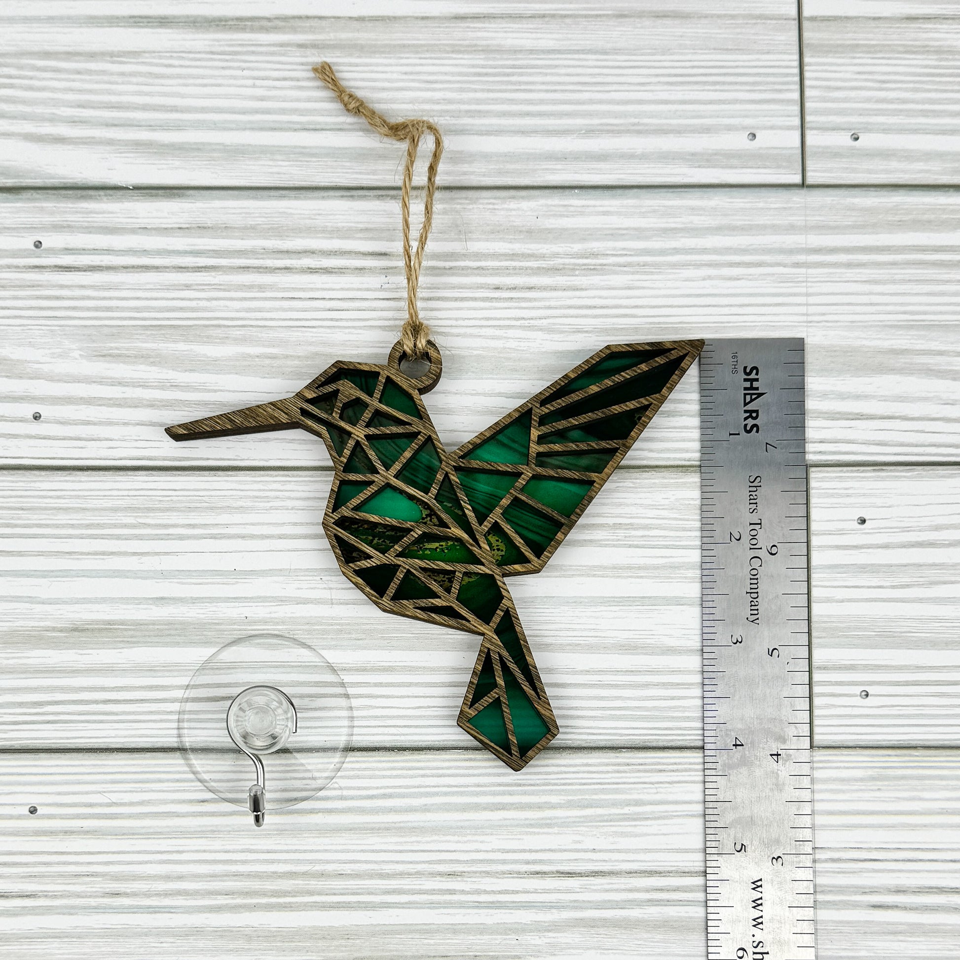 Hummingbird suncatcher made from wood and acrylic lying flat with a ruler showing the approximate height.