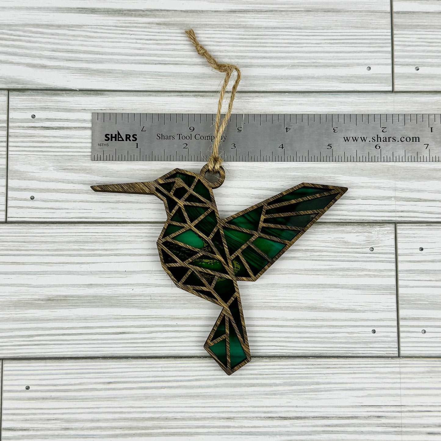 Hummingbird suncatcher made from wood and acrylic lying flat with a ruler showing the approximate width.