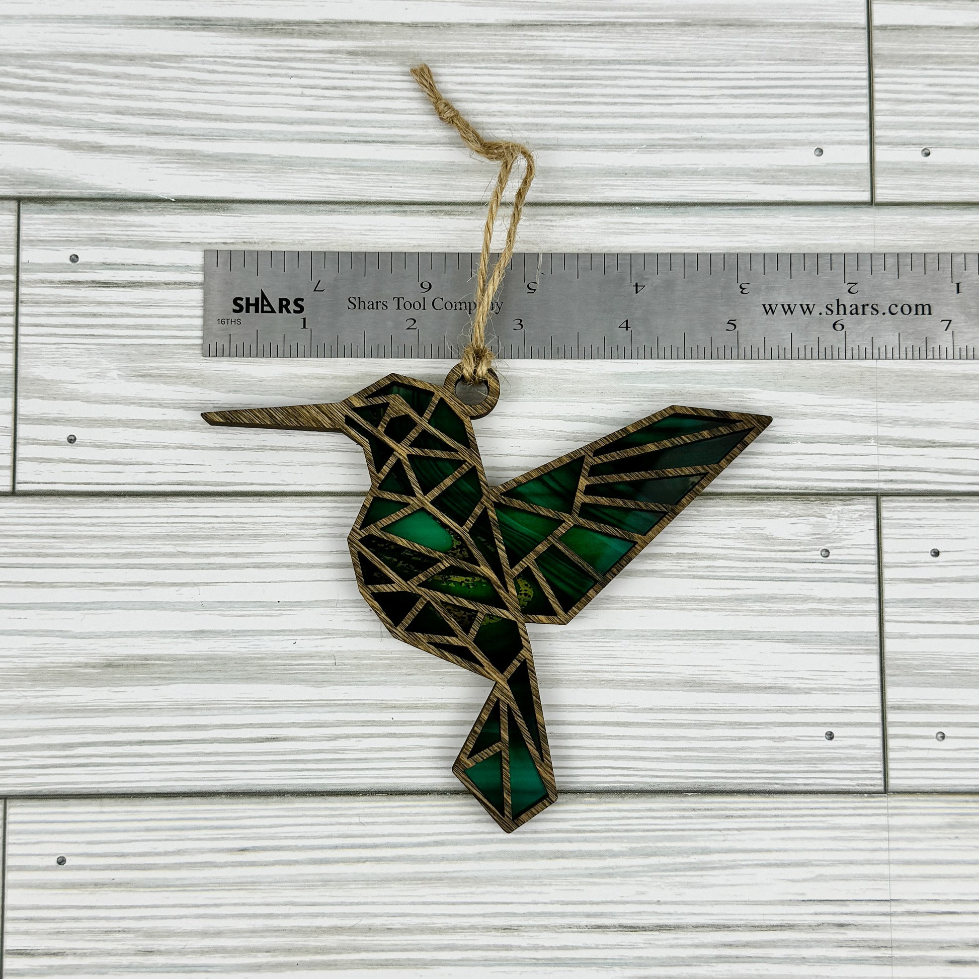 Hummingbird suncatcher made from wood and acrylic lying flat with a ruler showing the approximate width.