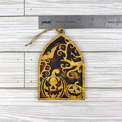 Jack-o'-lantern suncatcher made from wood and acrylic lying flat with a ruler showing the approximate width.