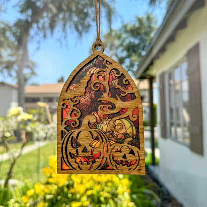Jack-o'-lantern suncatcher made from wood and acrylic hanging in window.