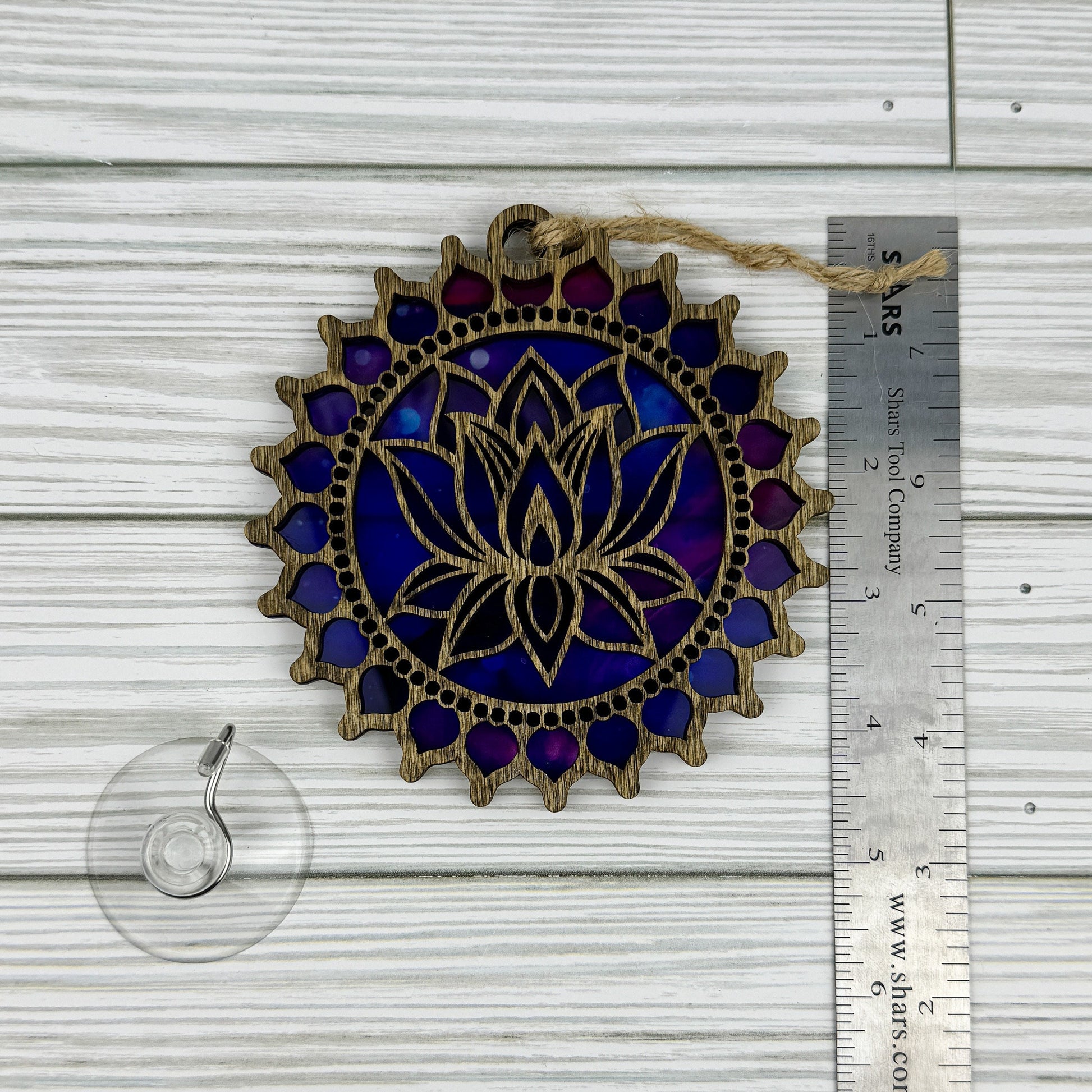 Lotus flower suncatcher made from wood and acrylic lying flat with a ruler showing the approximate height.