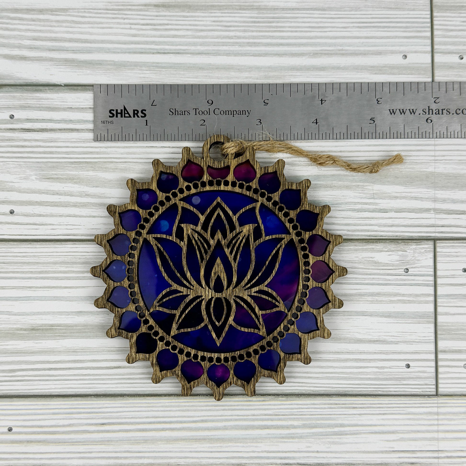 Lotus flower suncatcher made from wood and acrylic lying flat with a ruler showing the approximate width.