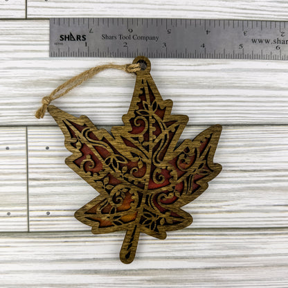 Maple leaf suncatcher made from wood and acrylic lying flat with a ruler showing the approximate width.