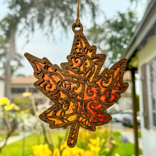 Maple leaf suncatcher made from wood and acrylic hanging in window.
