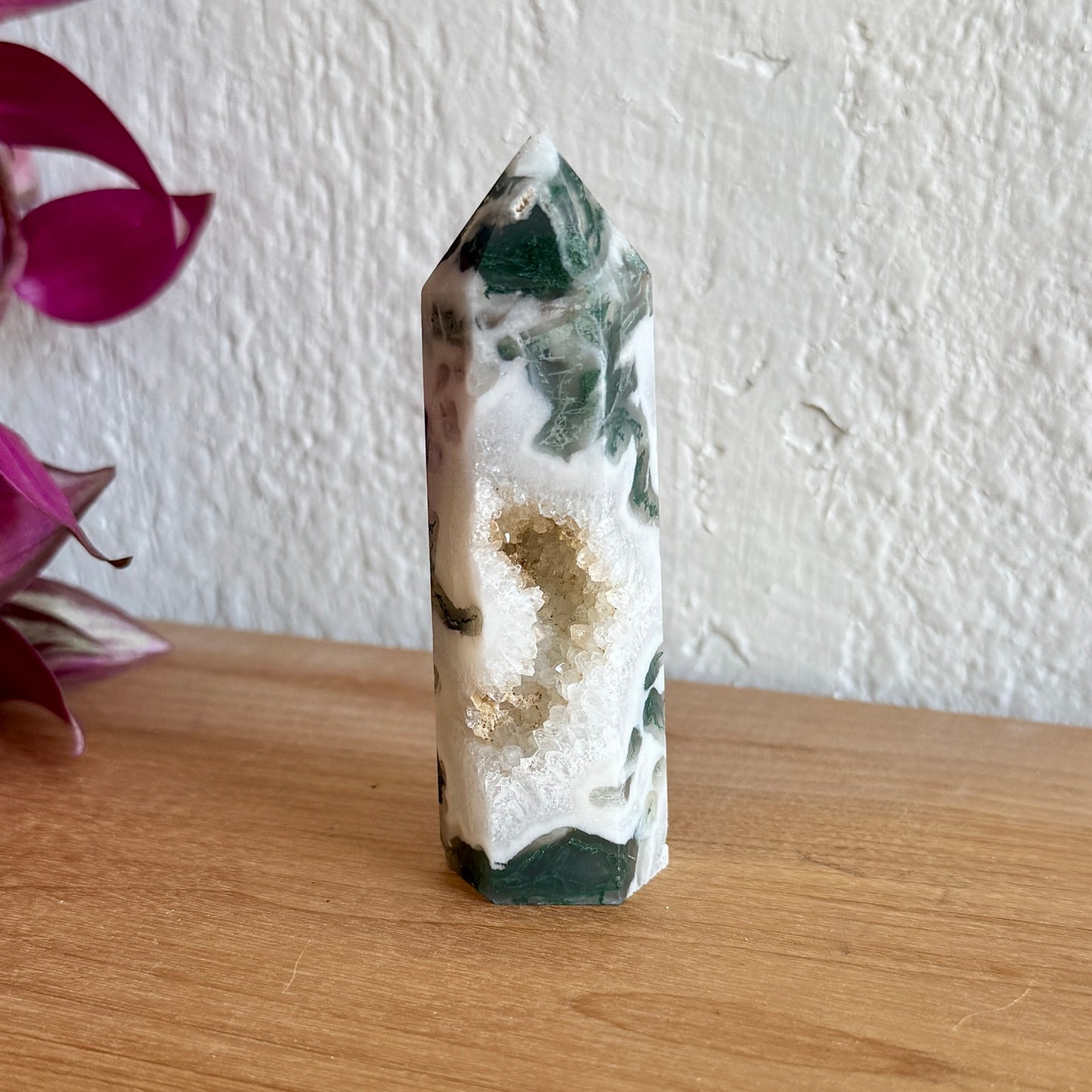 Crystal tower with green and white patterns on a wooden surface with a blurred background
