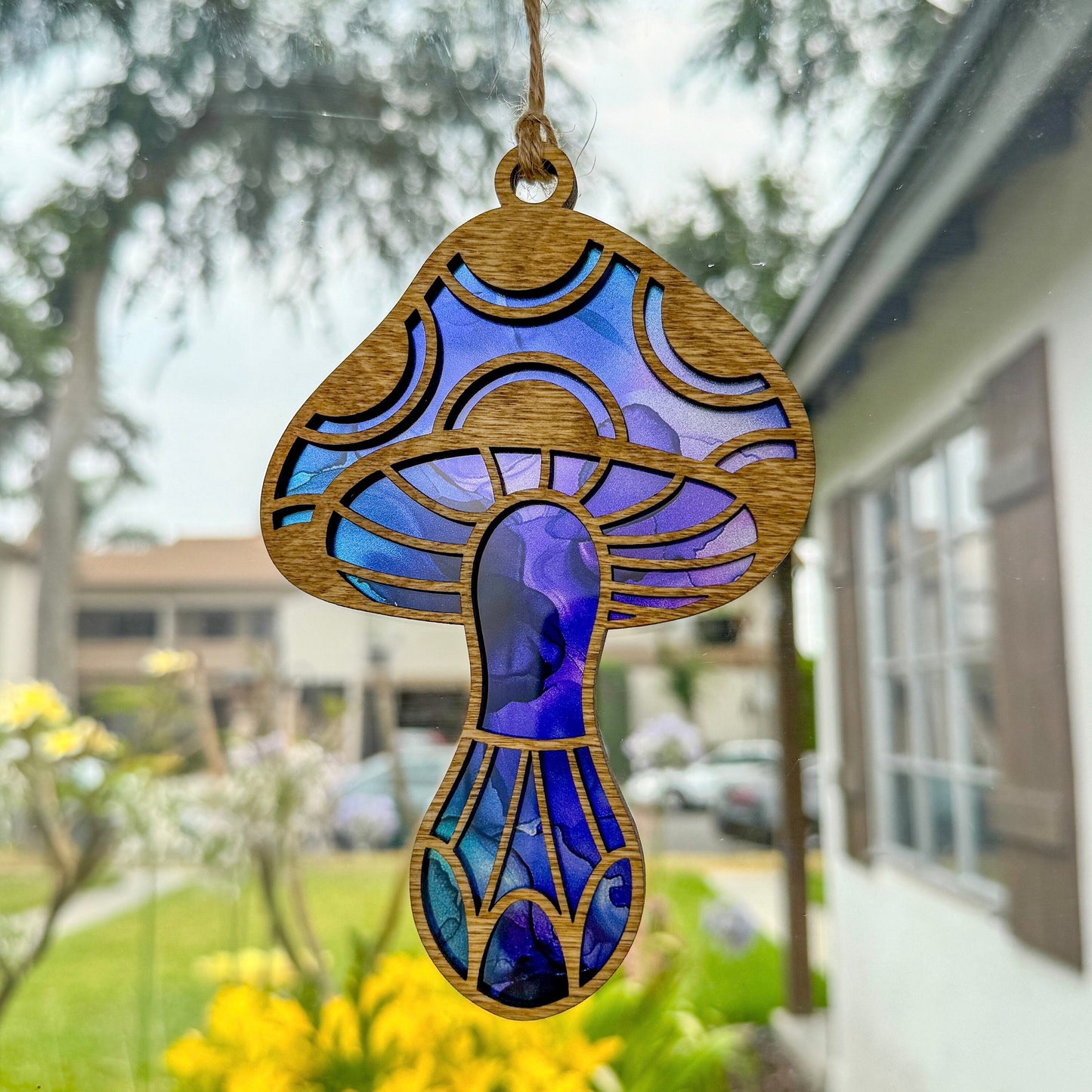 Mushroom suncatcher made from wood and acrylic with a blue and purple pattern hanging in window 
