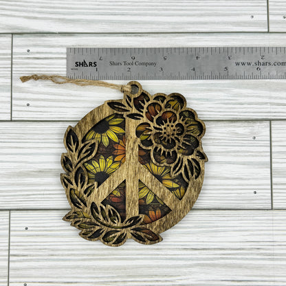 Wooden peace symbol suncatcher with floral design next to a ruler showing approximate width on a wooden surface