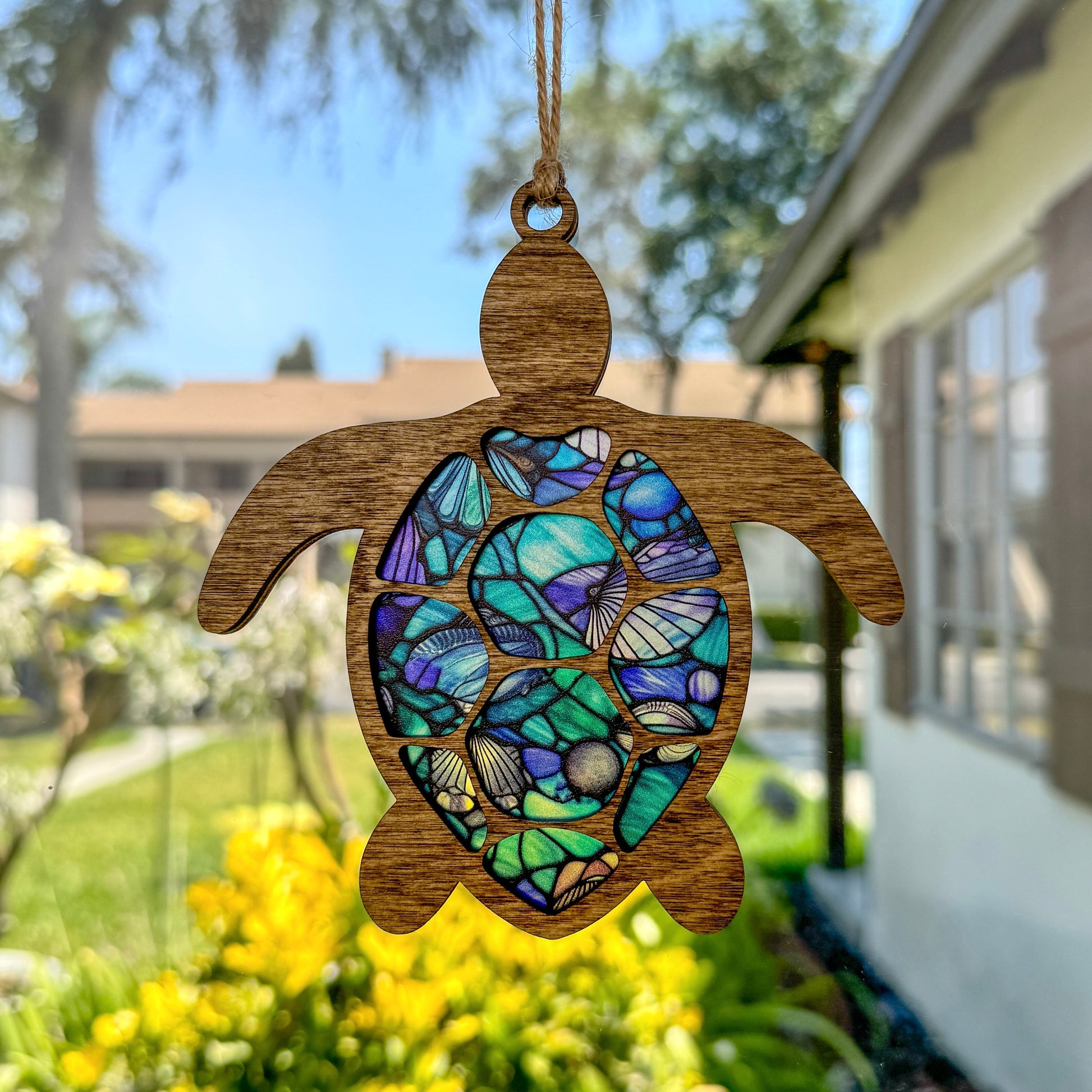 Sea turtle suncatcher made from wood and acrylic hanging in window.