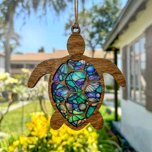Sea turtle suncatcher made from wood and acrylic hanging in window.