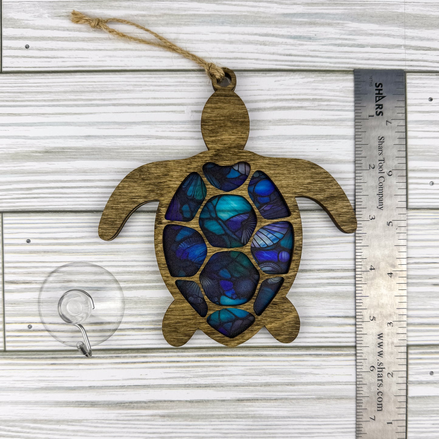 Sea turtle suncatcher made from wood and acrylic lying flat with a ruler showing the approximate height.