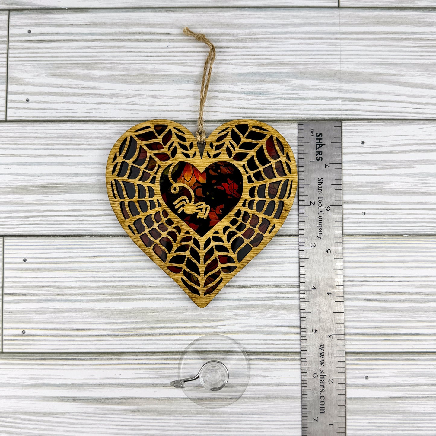 Spiderweb heart shaped suncatcher made from wood and acrylic lying flat with a ruler showing the approximate height.
