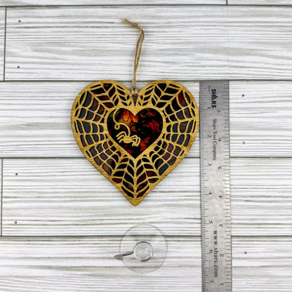 Spiderweb heart shaped suncatcher made from wood and acrylic lying flat with a ruler showing the approximate height.