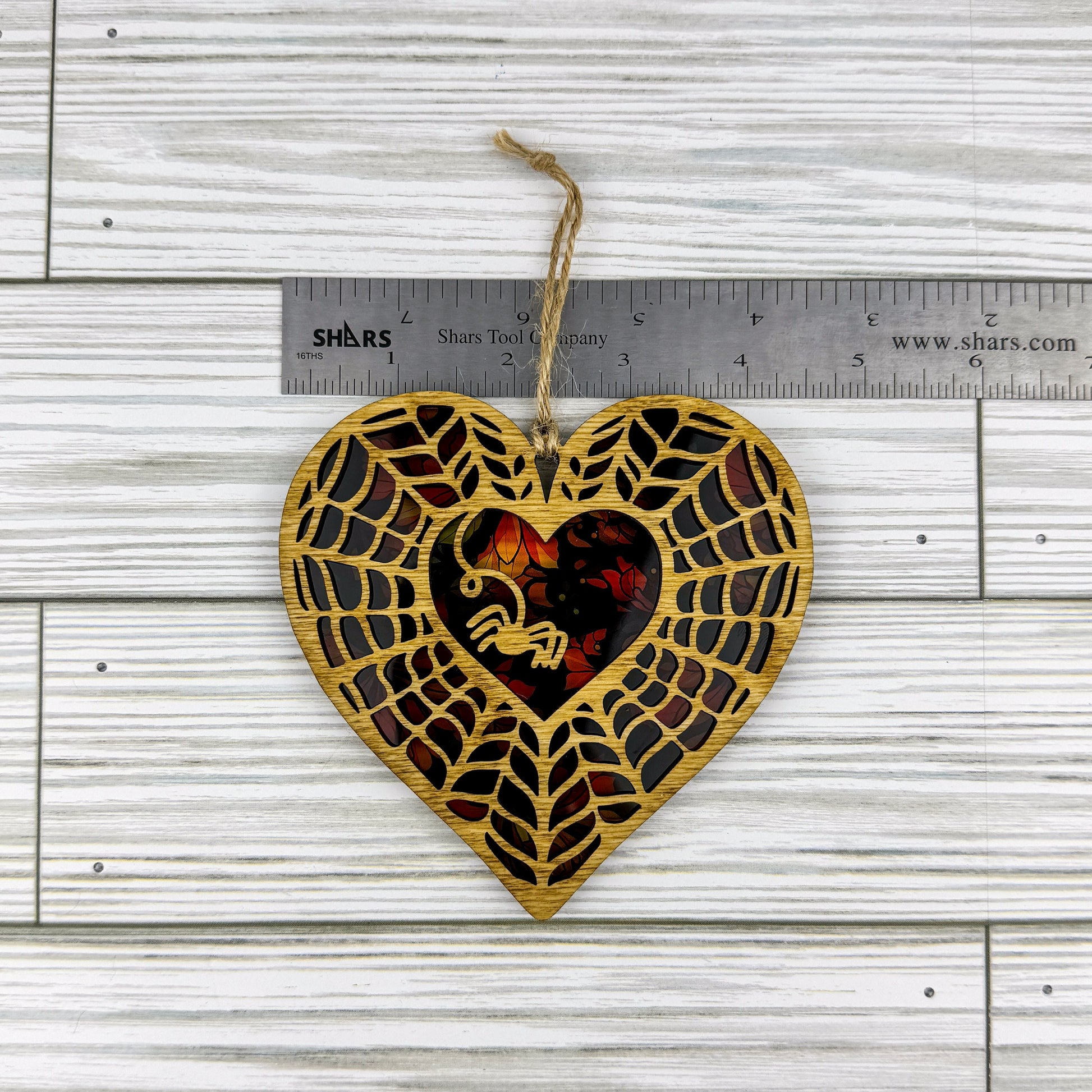Spiderweb heart shaped suncatcher made from wood and acrylic lying flat with a ruler showing the approximate width.
