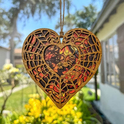 Spiderweb heart shaped suncatcher made from wood and acrylic hanging in window.