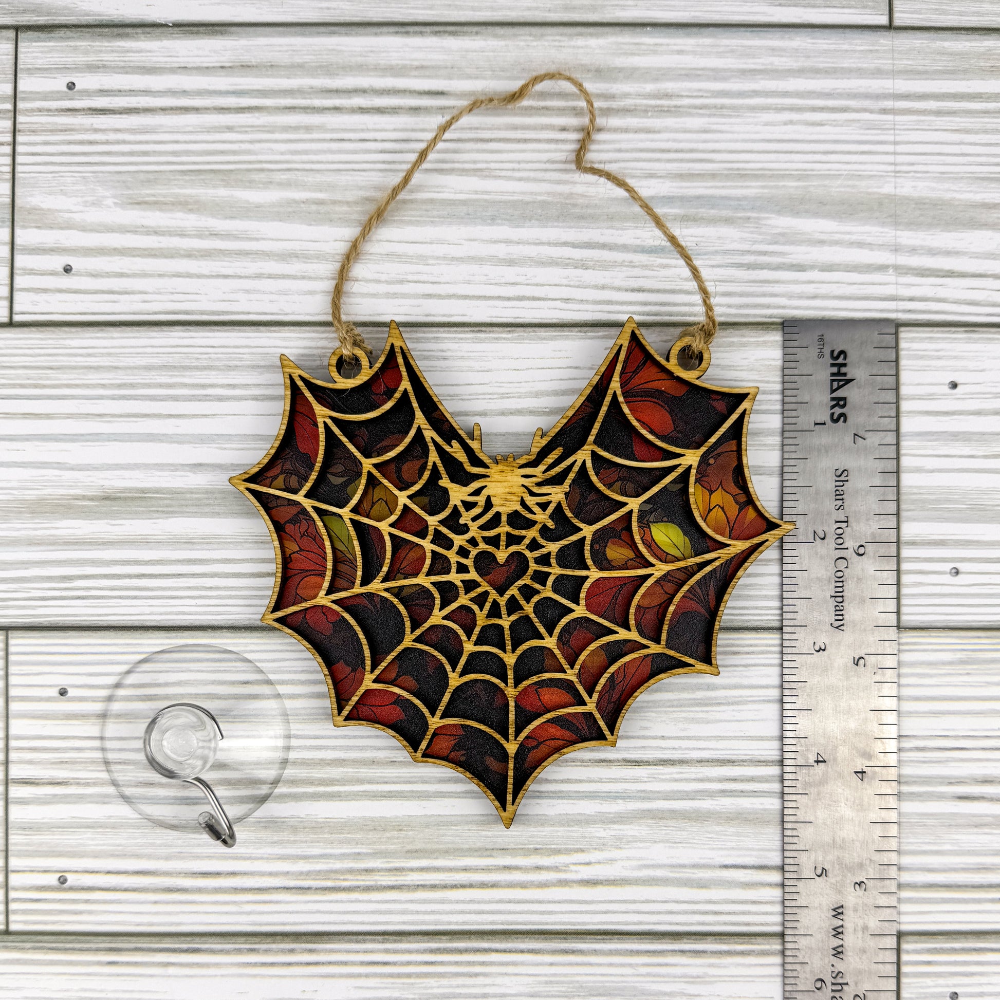Spiderweb suncatcher made from wood and acrylic lying flat with a ruler showing the approximate height.