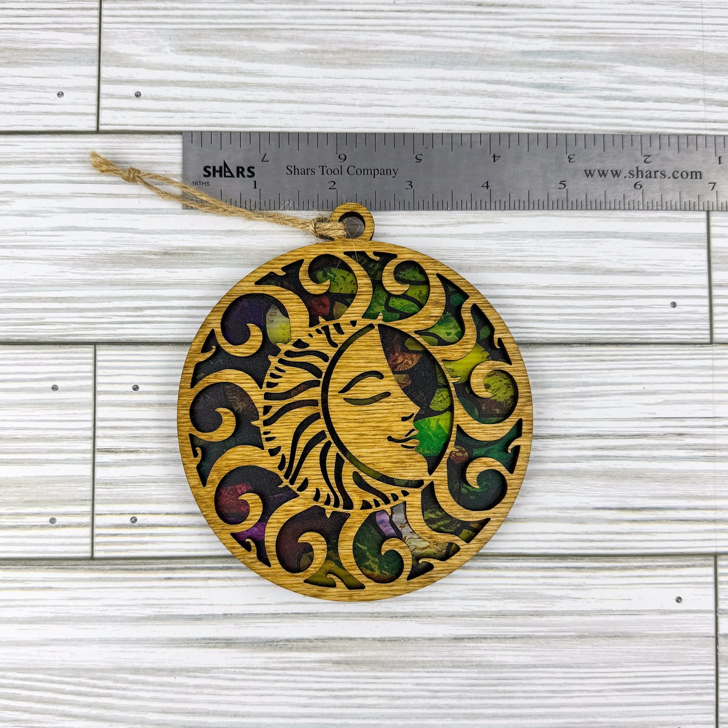 Sun suncatcher made from wood and acrylic lying flat with a ruler showing the approximate width.